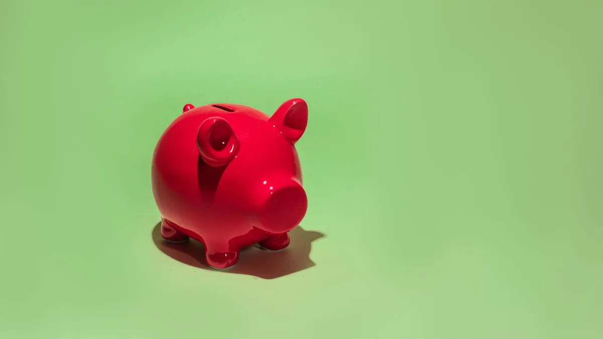 A piggy bank beside a growing plant