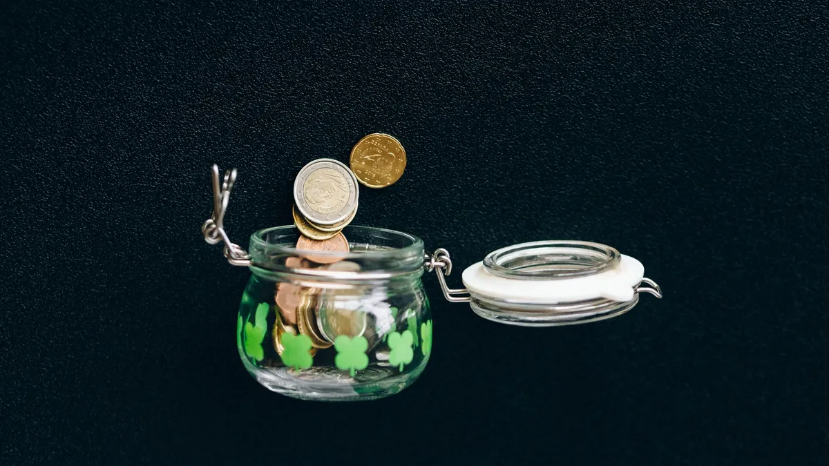 Coins in a jar with a small plant