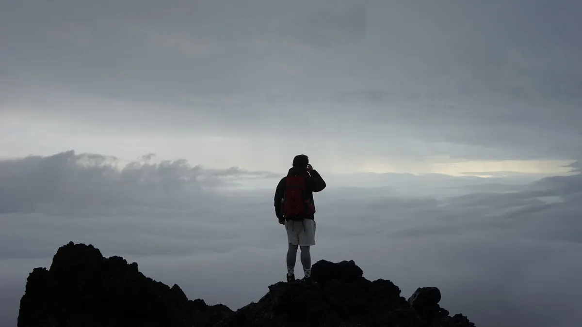 A hiker reaching a mountain summit